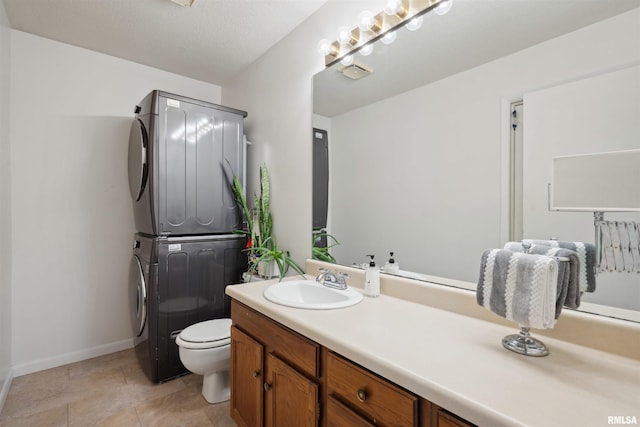 bathroom featuring vanity, baseboards, stacked washer and clothes dryer, and toilet