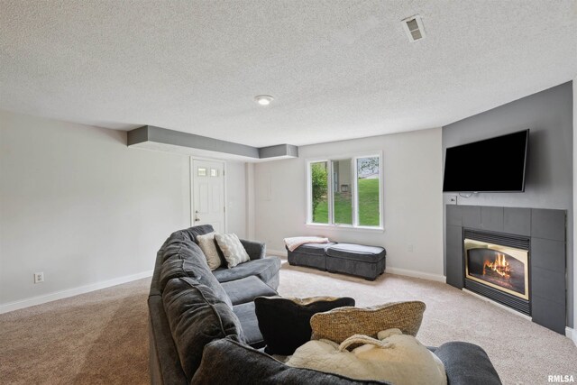carpeted living room with visible vents, baseboards, a textured ceiling, and a tiled fireplace
