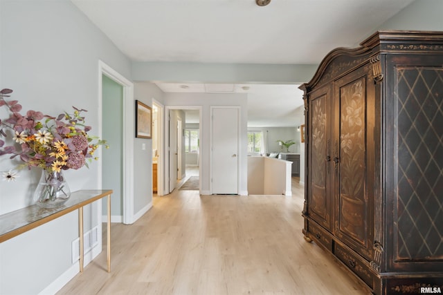 hall with light wood-style floors, baseboards, and visible vents
