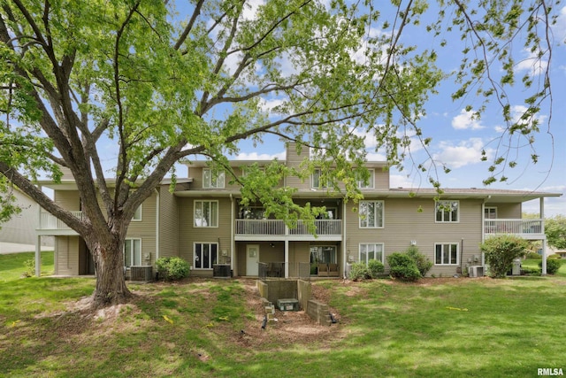 rear view of house with a yard, central AC, and a balcony