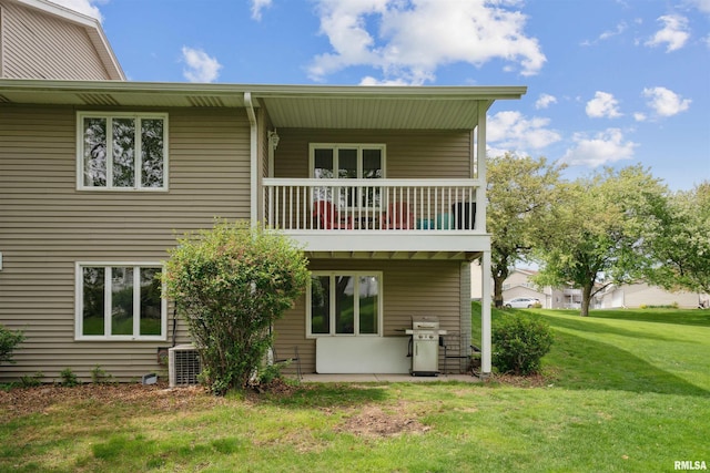 rear view of property featuring a lawn and a balcony