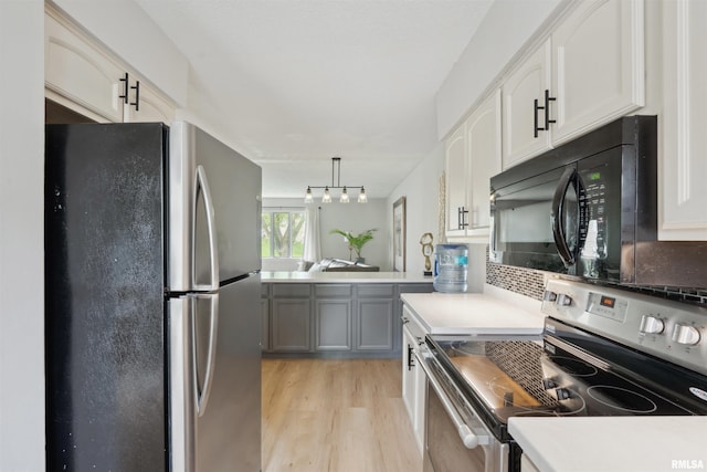 kitchen with stainless steel appliances, white cabinetry, decorative backsplash, light wood-type flooring, and pendant lighting