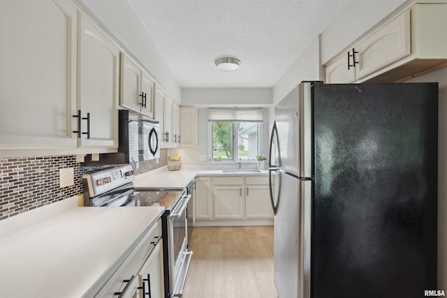 kitchen featuring tasteful backsplash, light wood-type flooring, a sink, light countertops, and stainless steel appliances