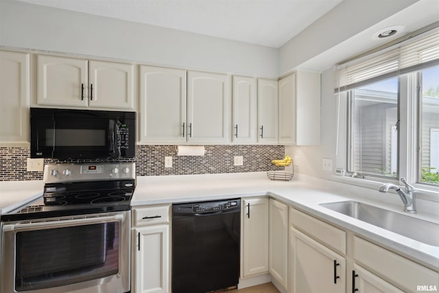 kitchen featuring decorative backsplash, light countertops, white cabinets, a sink, and black appliances