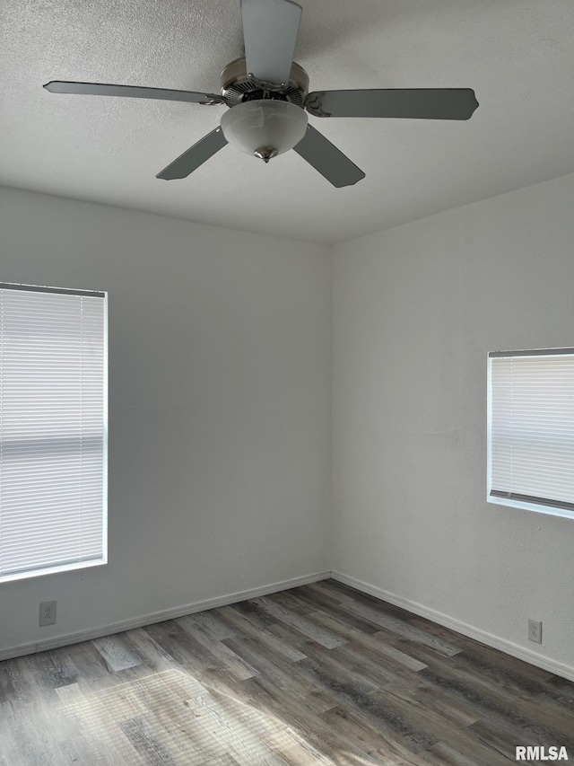 spare room with a ceiling fan, baseboards, and dark wood-type flooring