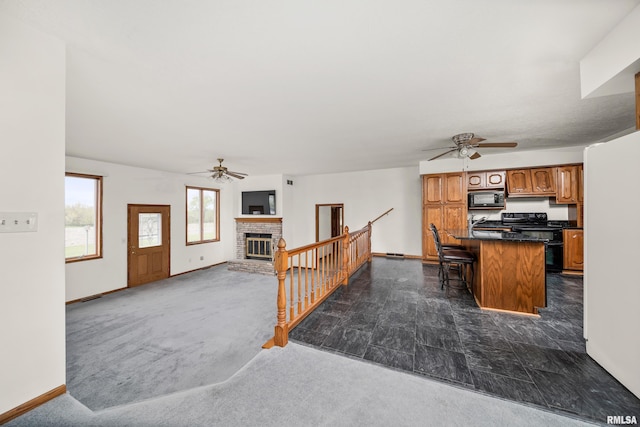 kitchen featuring stove, black microwave, a fireplace, and ceiling fan