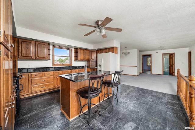 kitchen with white refrigerator with ice dispenser, ceiling fan, a kitchen bar, open shelves, and brown cabinets
