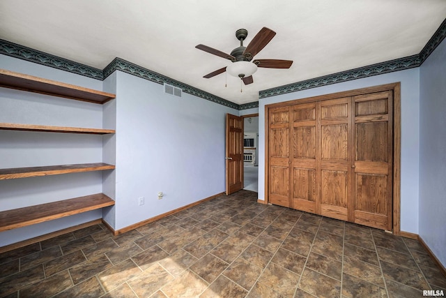 unfurnished bedroom with a closet, stone finish floor, baseboards, ceiling fan, and visible vents