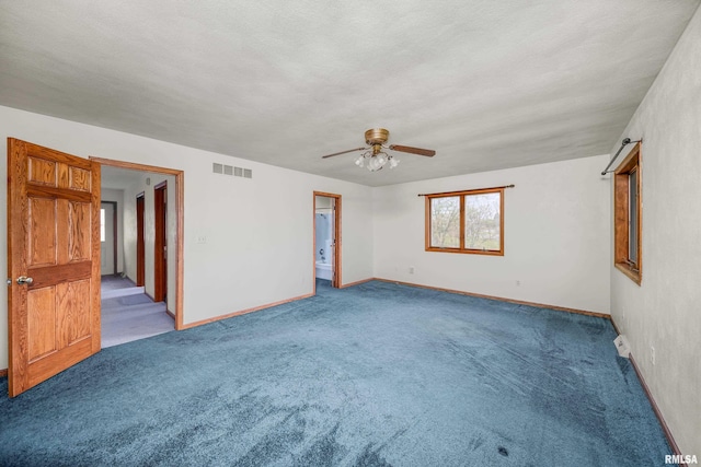 carpeted spare room featuring visible vents, baseboards, and a ceiling fan
