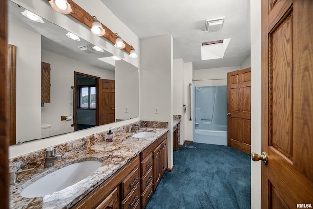bathroom featuring double vanity, toilet, a skylight, and a sink
