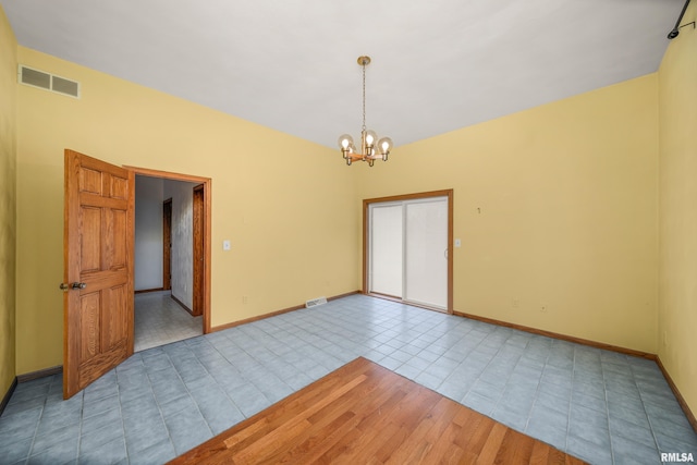 tiled empty room with a chandelier, baseboards, and visible vents
