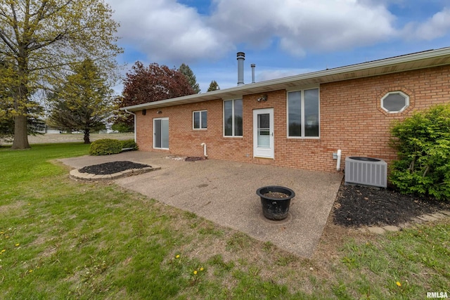 back of house featuring central AC unit, a patio area, brick siding, and a lawn