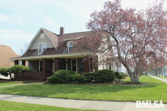 view of front of house featuring a chimney, brick siding, and a front yard