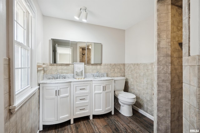 full bath featuring plenty of natural light, toilet, a sink, and tile walls