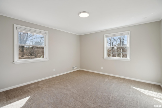 carpeted empty room with baseboards, ornamental molding, and visible vents
