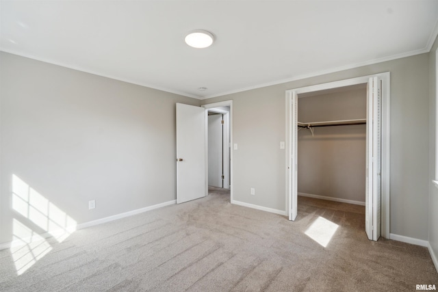 unfurnished bedroom featuring a walk in closet, a closet, crown molding, baseboards, and carpet flooring