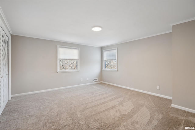 carpeted spare room with visible vents, baseboards, and ornamental molding