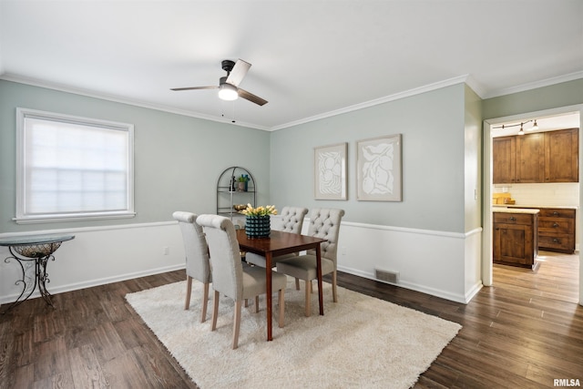 dining room with crown molding, visible vents, ceiling fan, and dark wood-style flooring