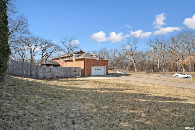 view of yard with an attached garage, fence, and driveway