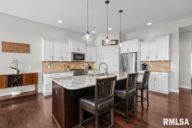 kitchen with decorative backsplash, appliances with stainless steel finishes, a sink, white cabinetry, and a textured ceiling
