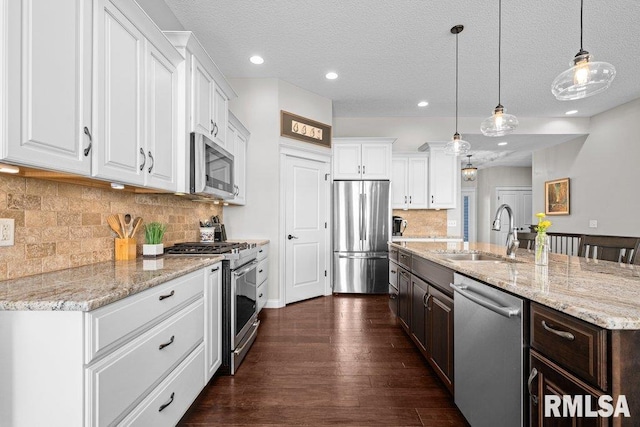 kitchen featuring dark brown cabinetry, an island with sink, appliances with stainless steel finishes, a sink, and white cabinetry