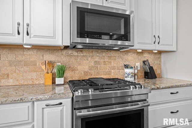 kitchen featuring white cabinetry, backsplash, appliances with stainless steel finishes, and light stone counters