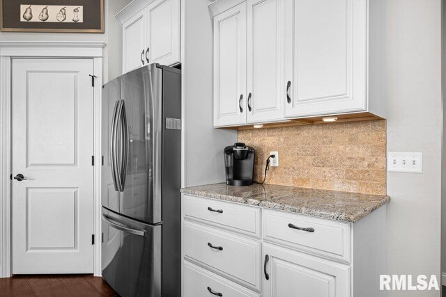 kitchen with white cabinets, backsplash, light stone counters, and freestanding refrigerator