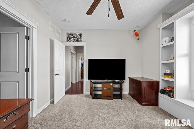 carpeted living room with a textured ceiling, visible vents, ceiling fan, and baseboards