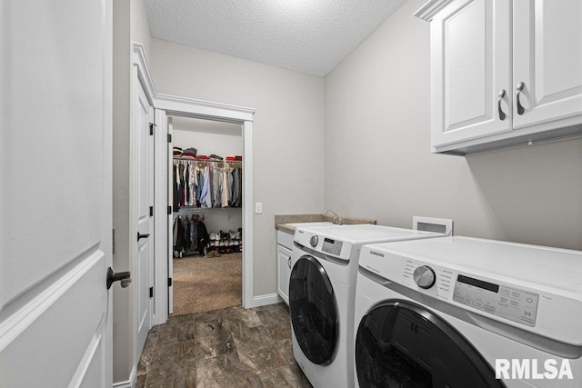 washroom featuring a textured ceiling, washer and dryer, cabinet space, and a sink