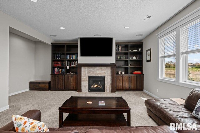 carpeted living area featuring a fireplace with flush hearth, a textured ceiling, and baseboards