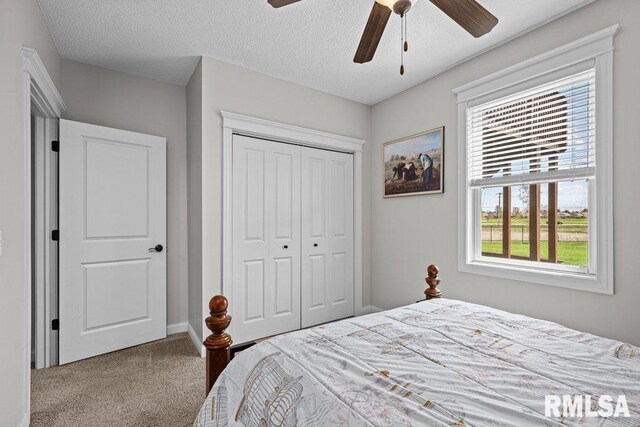 carpeted bedroom with a textured ceiling, ceiling fan, a closet, and multiple windows