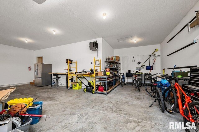 garage featuring a workshop area and stainless steel fridge with ice dispenser