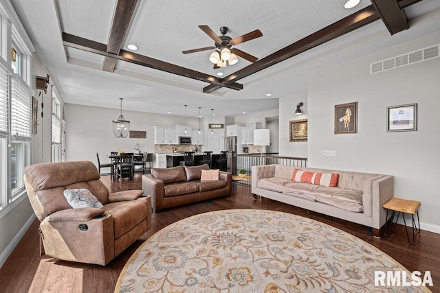 living area with visible vents, beamed ceiling, and baseboards