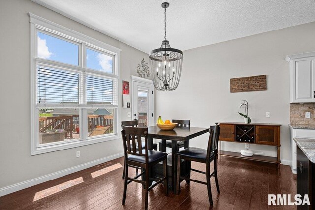 dining area with a textured ceiling, visible vents, dark wood-style floors, baseboards, and a notable chandelier