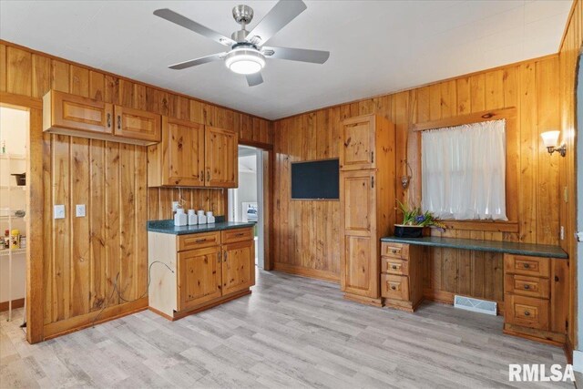 608 S Oakwood Ave, Geneseo, IL 61254 - kitchen with wooden walls, brown cabinets, a ceiling fan, light wood-type flooring, and dark countertops