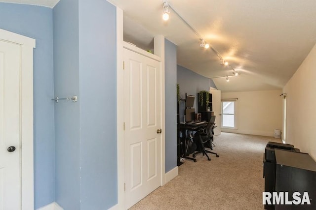 office featuring baseboards, track lighting, lofted ceiling, and light colored carpet