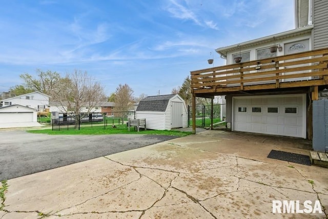 exterior space with fence, driveway, and a storage unit
