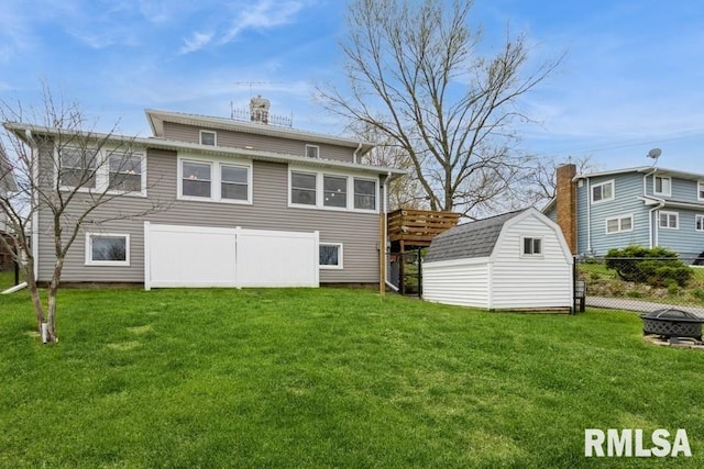 rear view of property featuring a storage shed, a lawn, a fire pit, fence, and an outbuilding