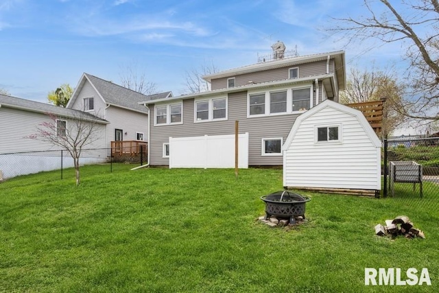 rear view of property featuring a fire pit, a storage shed, a fenced backyard, and a lawn
