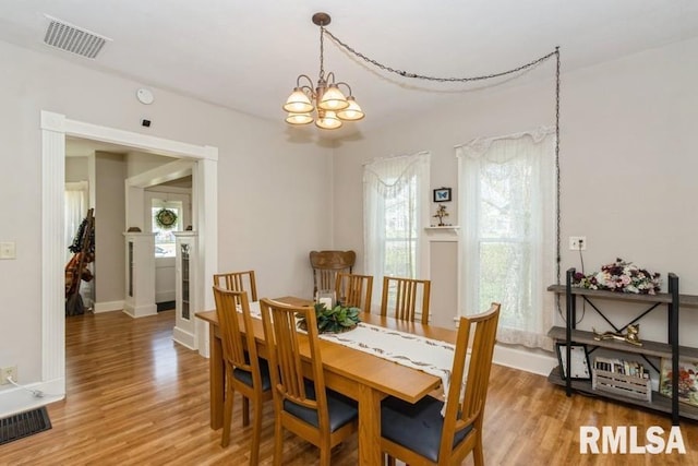 dining area with light wood finished floors, baseboards, visible vents, and a notable chandelier