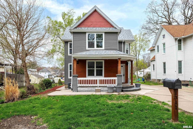 view of front of house with roof with shingles, a porch, and a front lawn