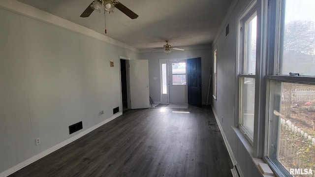 unfurnished room featuring dark wood-style flooring, ceiling fan, visible vents, and baseboards