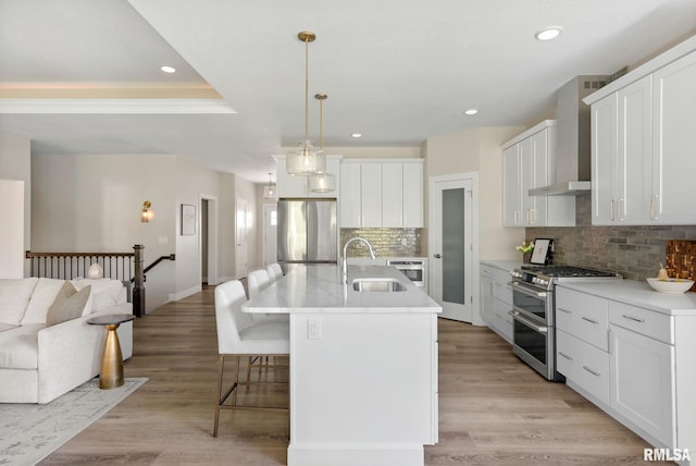 4048 Meadowlark Ct, Bettendorf, IA 52722 - kitchen with appliances with stainless steel finishes, wall chimney range hood, white cabinets, a kitchen bar, and a sink