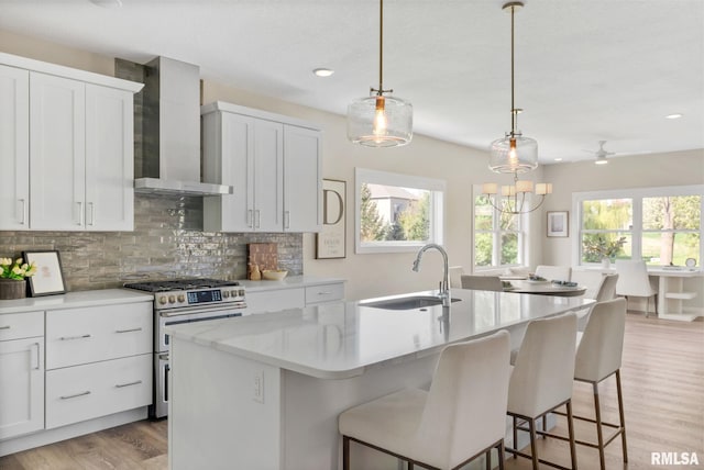4048 Meadowlark Ct, Bettendorf, IA 52722 - kitchen with wall chimney range hood, a sink, range with two ovens, an island with sink, and backsplash