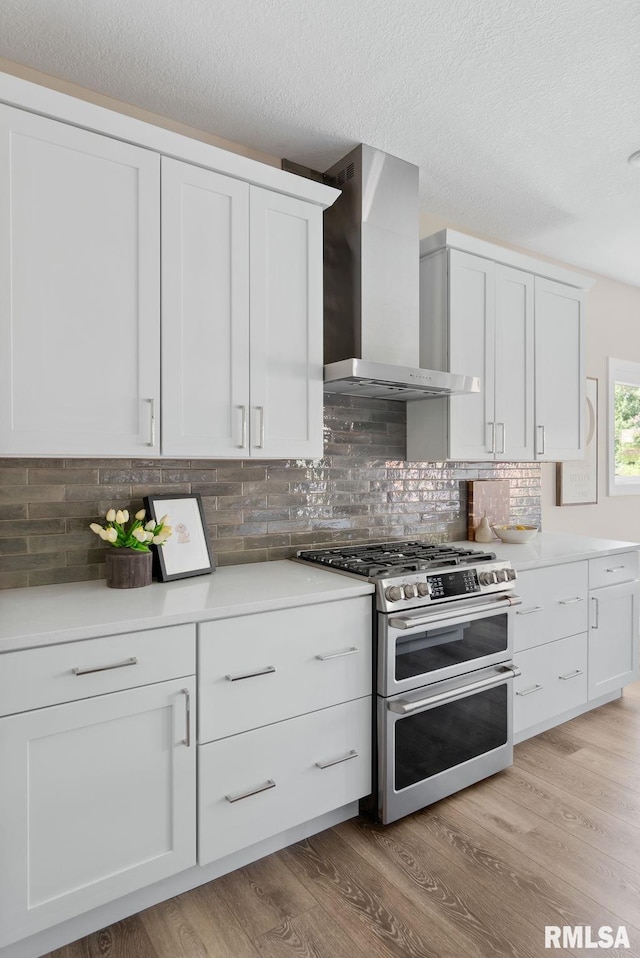 4048 Meadowlark Ct, Bettendorf, IA 52722 - kitchen with double oven range, white cabinets, light wood-style flooring, and wall chimney range hood