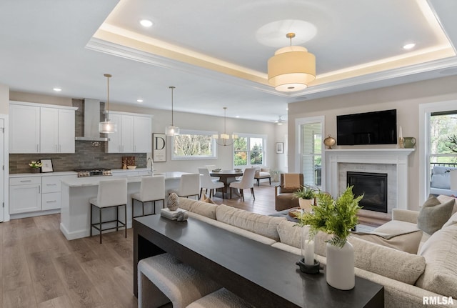 4048 Meadowlark Ct, Bettendorf, IA 52722 - living area with light wood finished floors, recessed lighting, a glass covered fireplace, and a tray ceiling