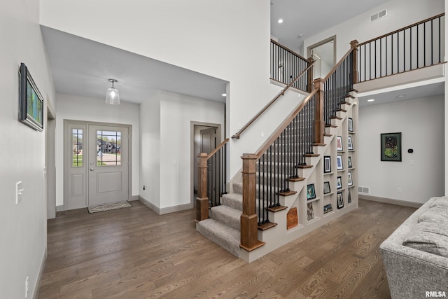 foyer featuring baseboards, visible vents, wood finished floors, and stairs