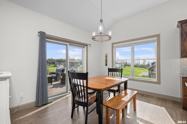 dining space featuring light wood-type flooring, vaulted ceiling, and baseboards