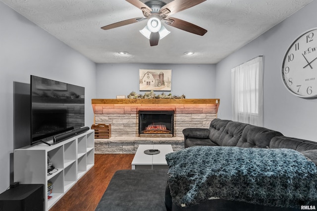 2149 W 30th St, Davenport, IA 52804 - living room featuring a stone fireplace, dark wood-style flooring, a ceiling fan, and a textured ceiling