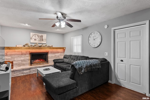 2149 W 30th St, Davenport, IA 52804 - living area featuring a ceiling fan, dark wood-type flooring, a stone fireplace, and a textured ceiling